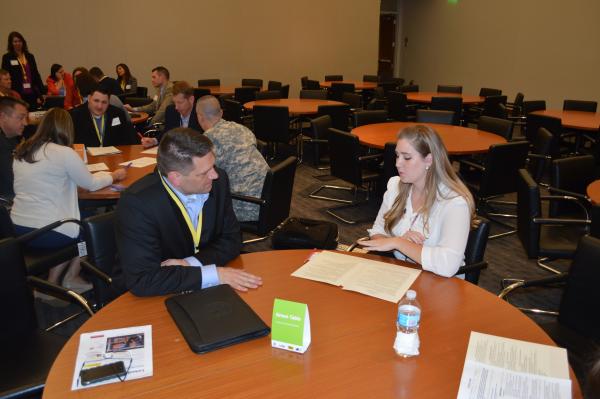 man and woman sitting at round table talking 