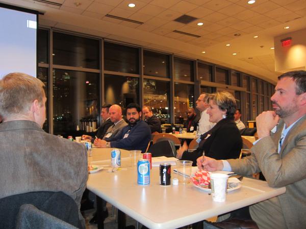 Some of the attendees sitting at a long table taking notes