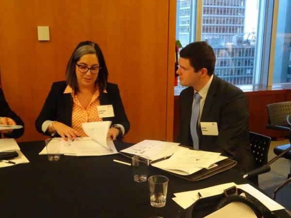 man and woman sitting at table talking and looking at papers